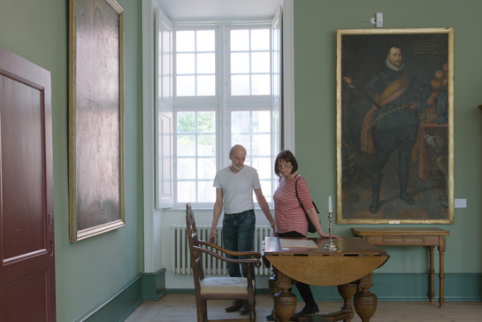 Zwei Besucher des Schloss Husum fassen einen alten Holztisch an