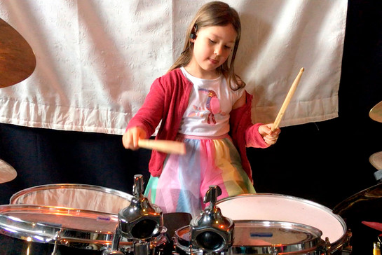 Ein kleines Mädchen spielt Schlagzeug